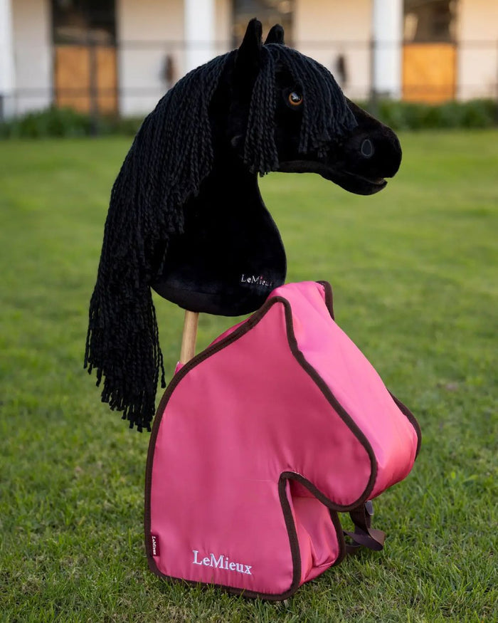 Cranberry coloured LeMieux Hobby Horse Carry Bag on garden background #colour_cranberry