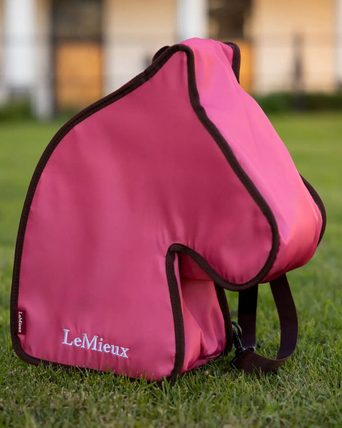 Cranberry coloured LeMieux Hobby Horse Carry Bag on garden background #colour_cranberry
