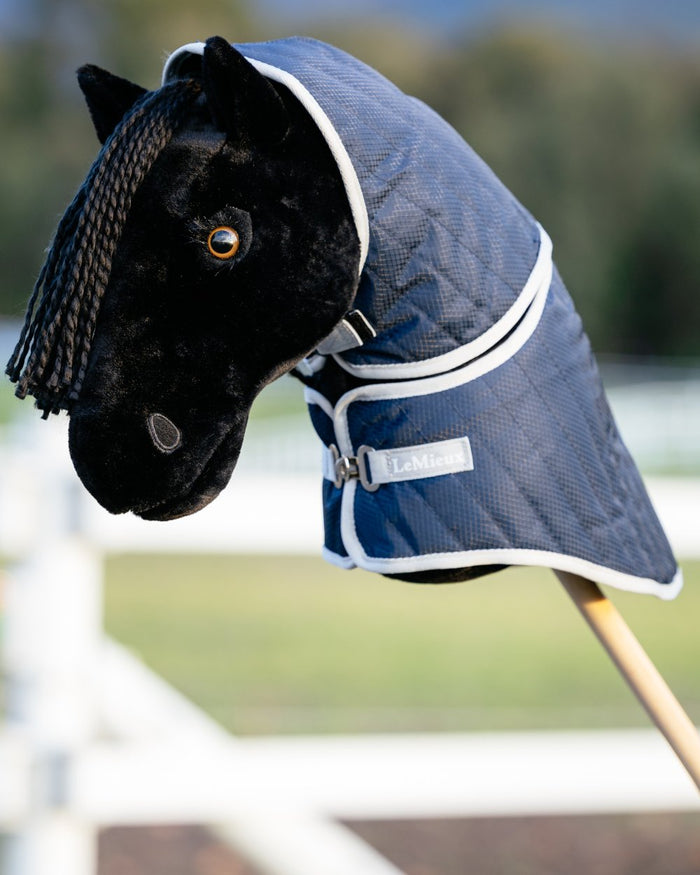 Navy coloured LeMieux Hobby Horse Stable Rug on blurry background #colour_navy