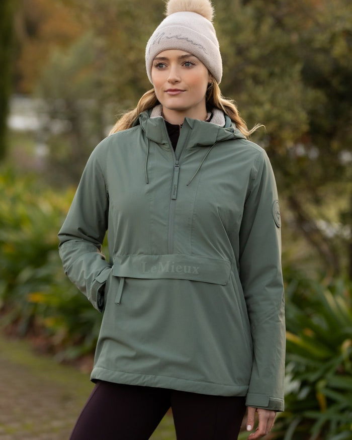 Rosemary coloured LeMieux Phoebe Half Zip Waterproof Anorak on tree background #colour_rosemary