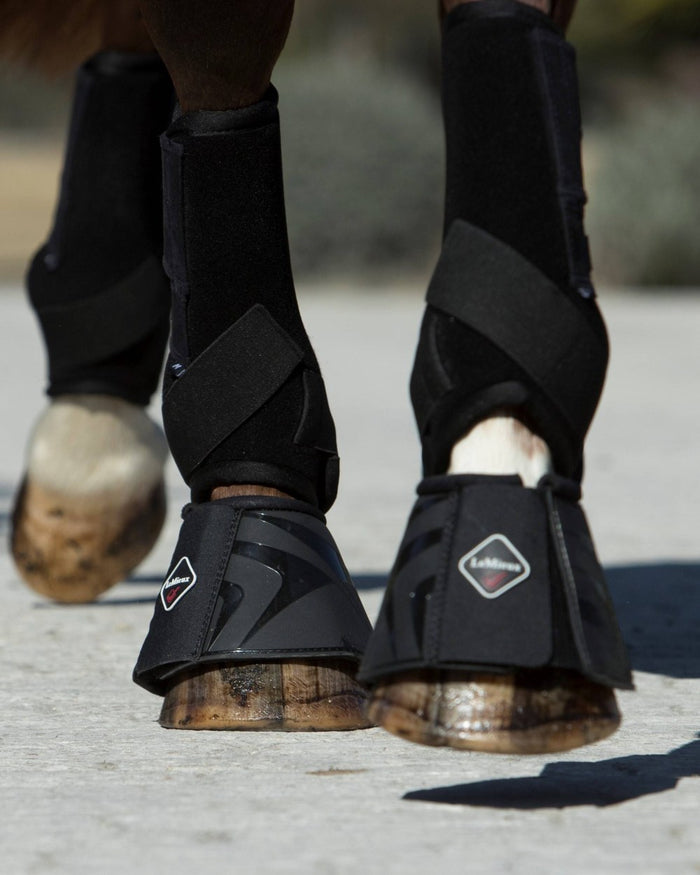 Black coloured LeMieux ProShell Over Reach Boots on blurry background #colour_black