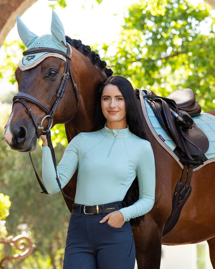 Aqua coloured LeMieux Womens Base Layer on blurry background #colour_aqua