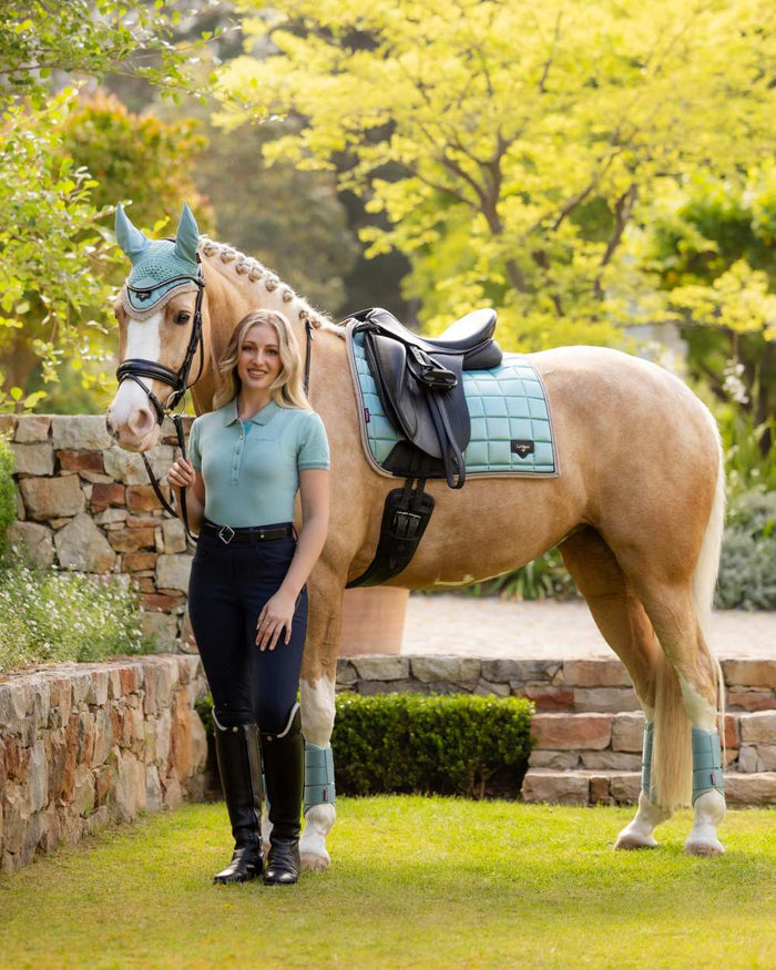 Aqua coloured LeMieux Womens Classique Polo Shirt on backyard background #colour_aqua