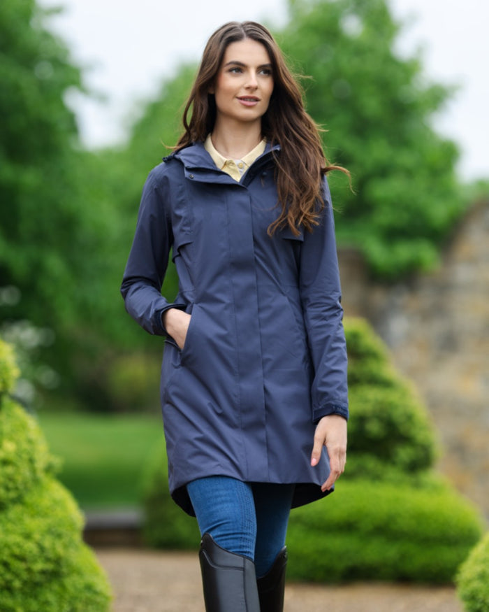 Dusk Blue coloured LeMieux Womens Grace Long Rain Jacket on blurry background #colour_dusk-blue