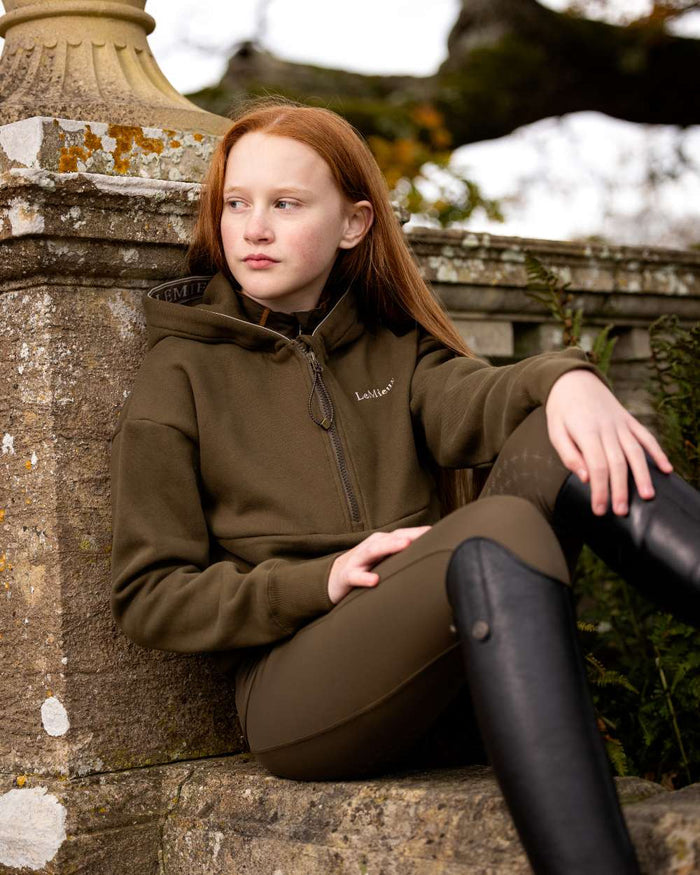 Alpine Coloured LeMieux Young Rider Hettie Half Zip Hoodie On A Outer Yard Background #colour_alpine