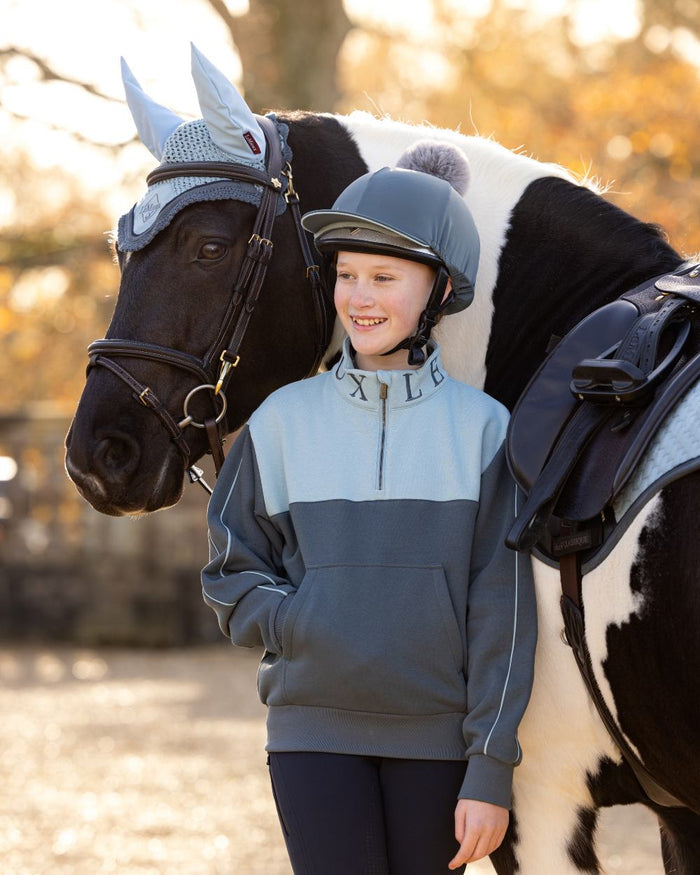 Petrol Glacier Coloured LeMieux Young Rider Kate Quarter Zip Sweater On A Outer Yard Background #colour_petrol-glacier