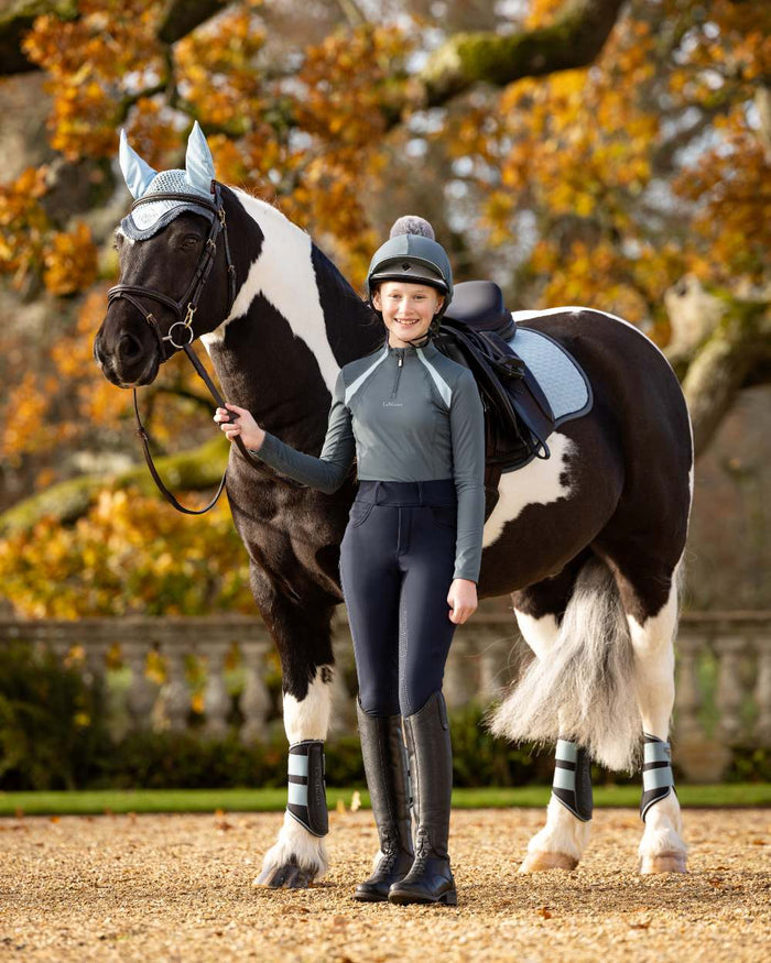 Petrol Coloured LeMieux Young Rider Mia Mesh Base Layer On A Yard Background #colour_petrol