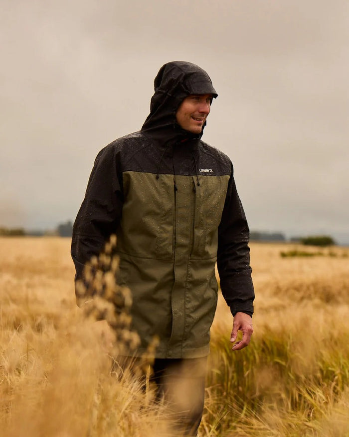 Moss Black Coloured Line 7 Mens Territory Storm Pro20 Waterproof Jacket on farm background #colour_moss-black