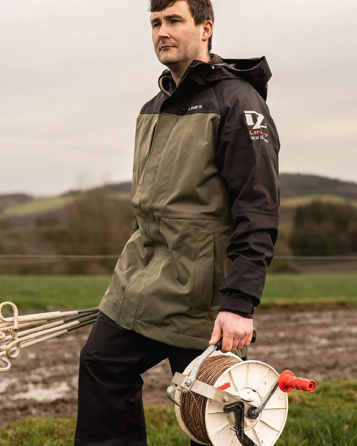 Moss Black Coloured Line 7 Mens Territory Storm Pro20 Waterproof Jacket on farm background #colour_moss-black