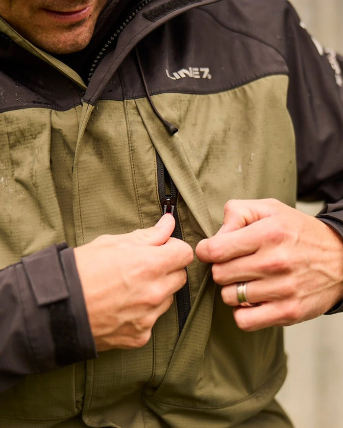 Moss Black Coloured Line 7 Mens Territory Storm Pro20 Waterproof Jacket on blurry background #colour_moss-black