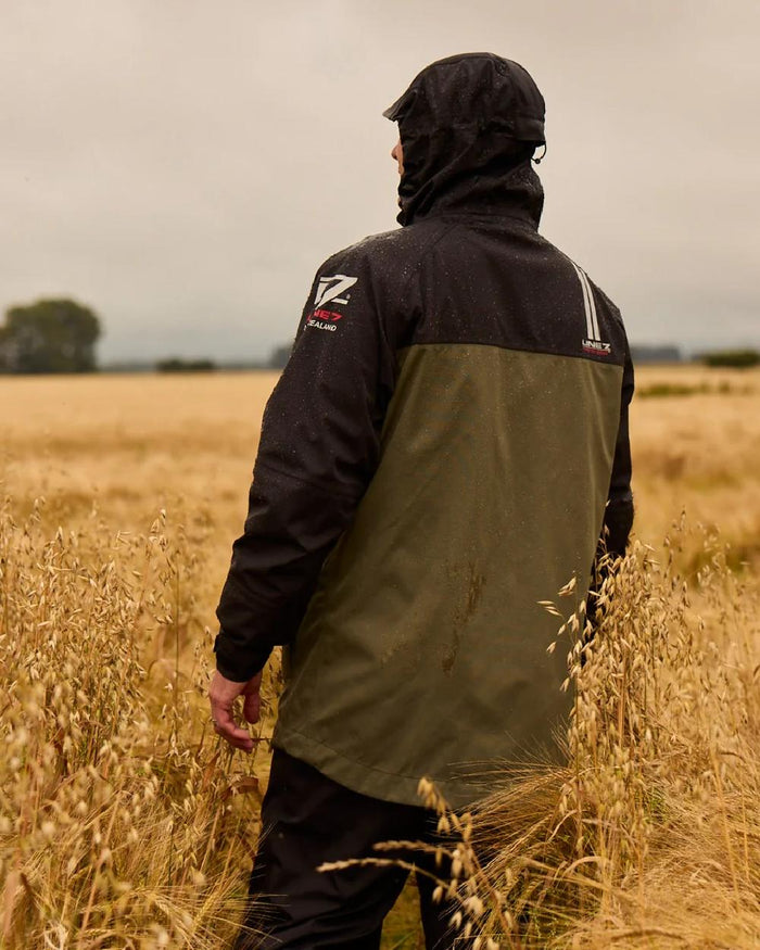 Moss Black Coloured Line 7 Mens Territory Storm Pro20 Waterproof Jacket on farm background #colour_moss-black