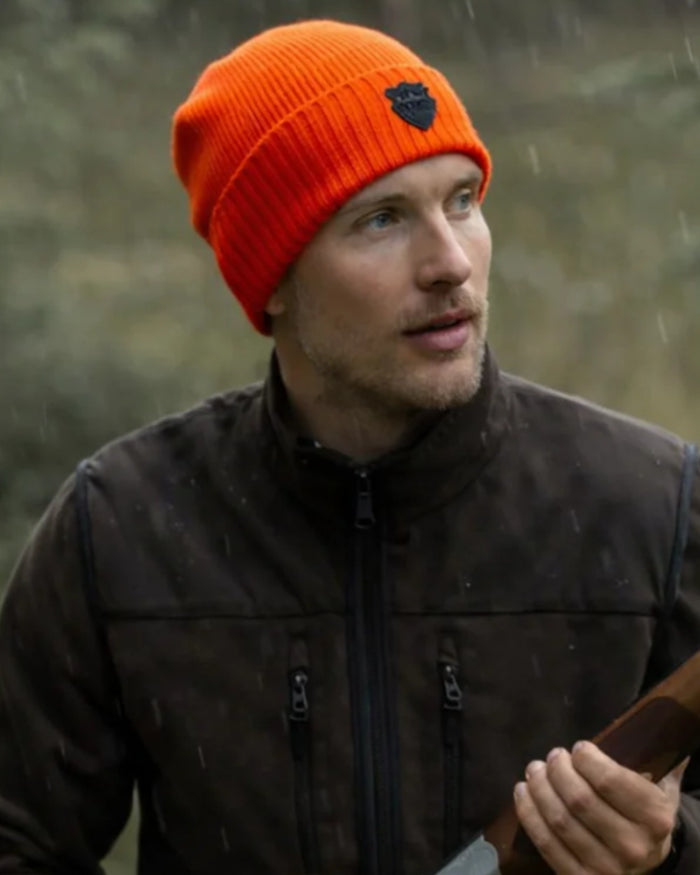 Orange coloured Northern Hunting Buk Windstop Beanie on forest background #colour_orange