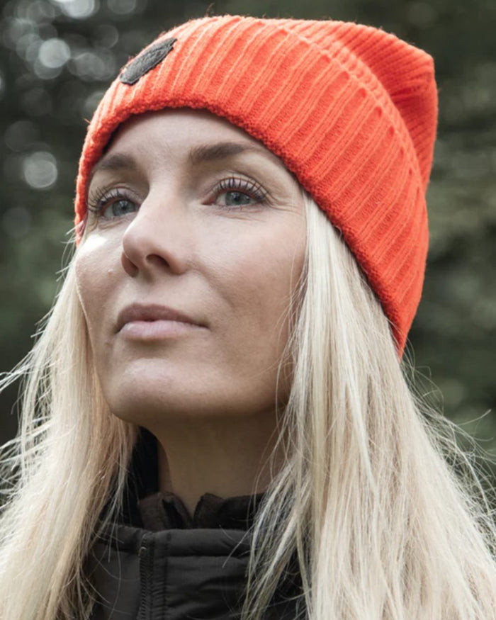 Orange coloured Northern Hunting Buk Windstop Beanie on forest background #colour_orange