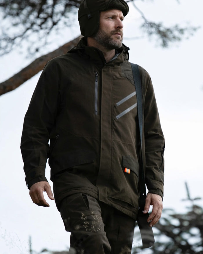 Dark Green coloured Northern Hunting Mens Thor Balder Waterproof Hunting Trousers on forest background #colour_dark-green