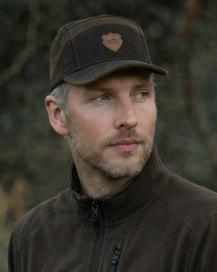 Dark Green coloured Northern Hunting Roald Cap on forest background #colour_dark-green