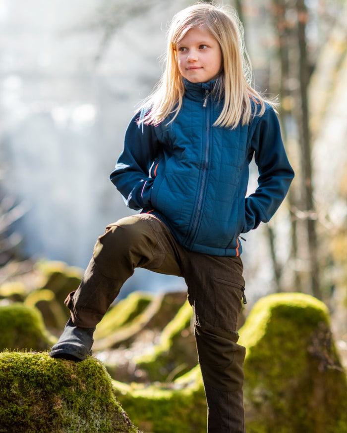 Suede Brown Dark Olive coloured Pinewood Childrens Caribou Hunt Trousers on forest background #colour_suede-brown-dark-olive