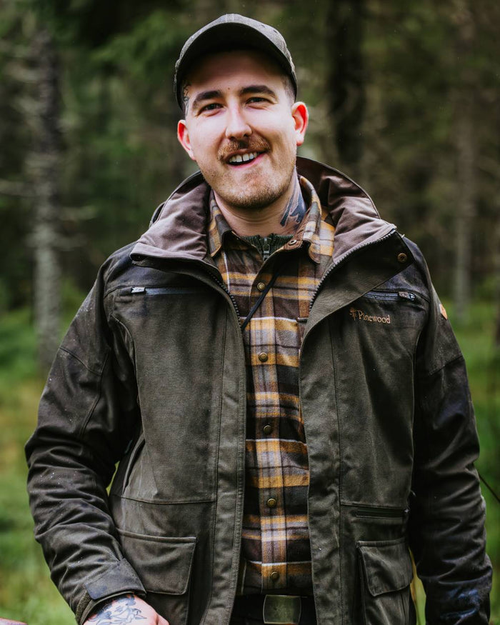 Dark Moss Green coloured Pinewood Mens Furudal Expert 2L Hunting Jacket on forest background #colour_dark-moss-green