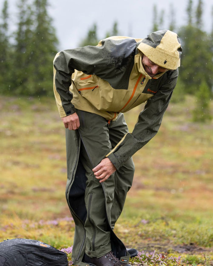 Moss Green Coloured Pinewood Mens Telluz Trousers on forest background #colour_moss-green