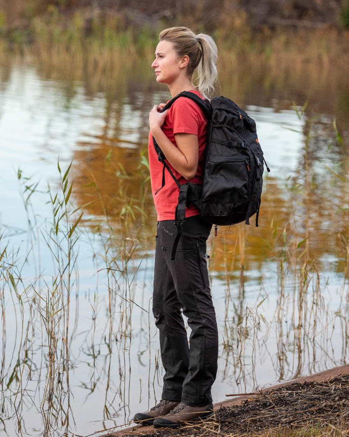 Black Coloured Pinewood Womens Abisko Brenton Trousers on lake background #colour_black