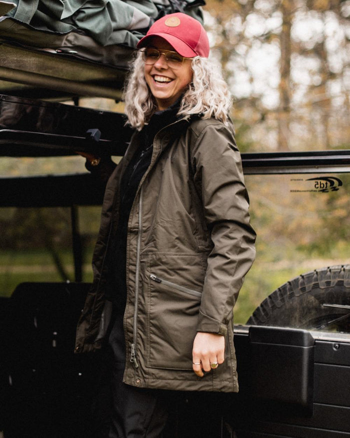 Moss Green coloured Pinewood Womens Wilda Parka on forest background #colour_moss-green
