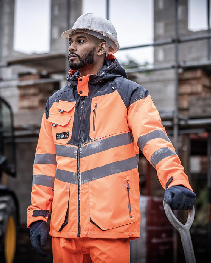 Orange Grey coloured Regatta Mens Hi-Vis Waterproof Reflective Parka Jacket on blurry background #colour_orange-grey