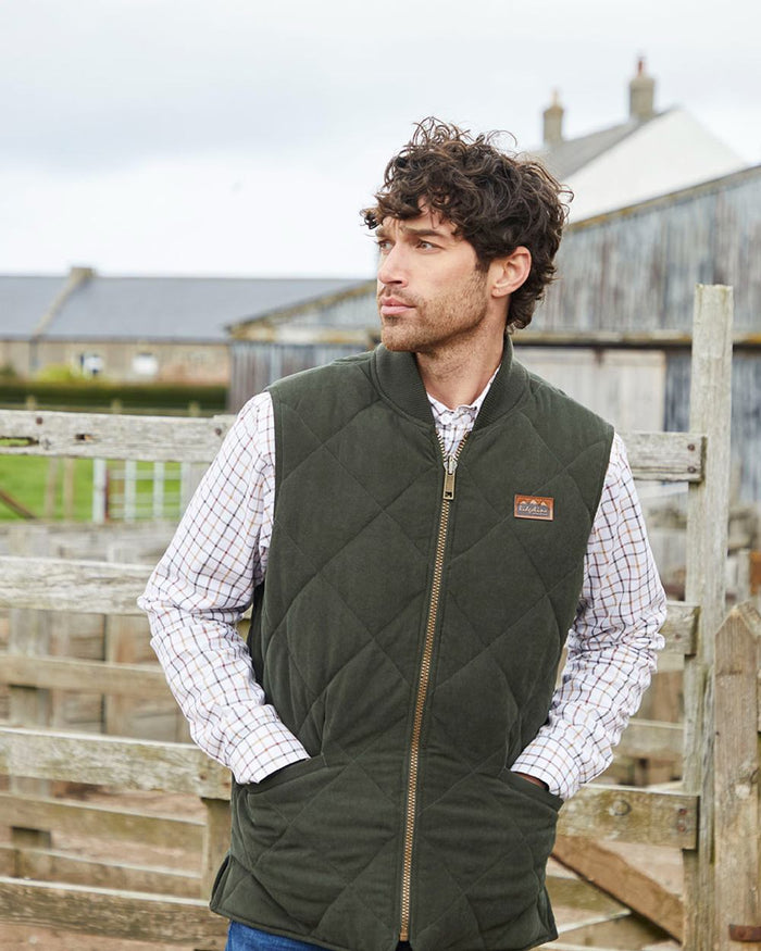 Deep Forest coloured Ridgeline Mens Wester Skeld Gilet on farm background #colour_deep-forest