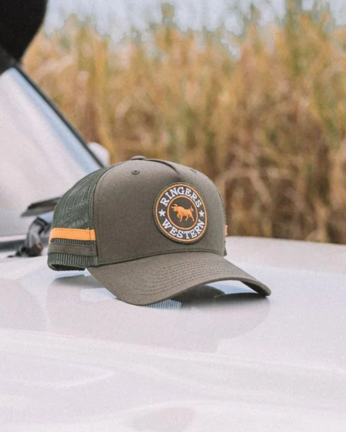 Olive coloured Ringers Western McCoy Trucker Cap on outdoor background #colour_olive