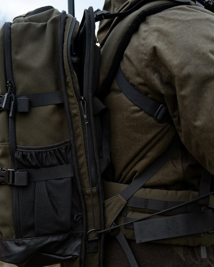 Pine Green coloured Seeland Enduro Backpack on forest background #colour_pine-green