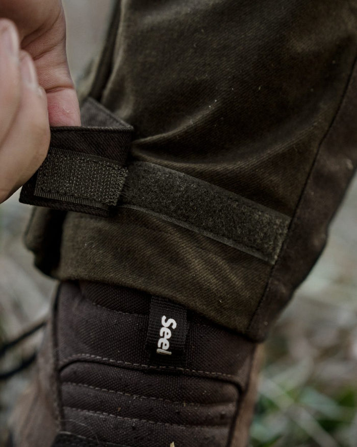 Pine Green Melange coloured Seeland Mens Quest Trousers on forest background #colour_pine-green-melange