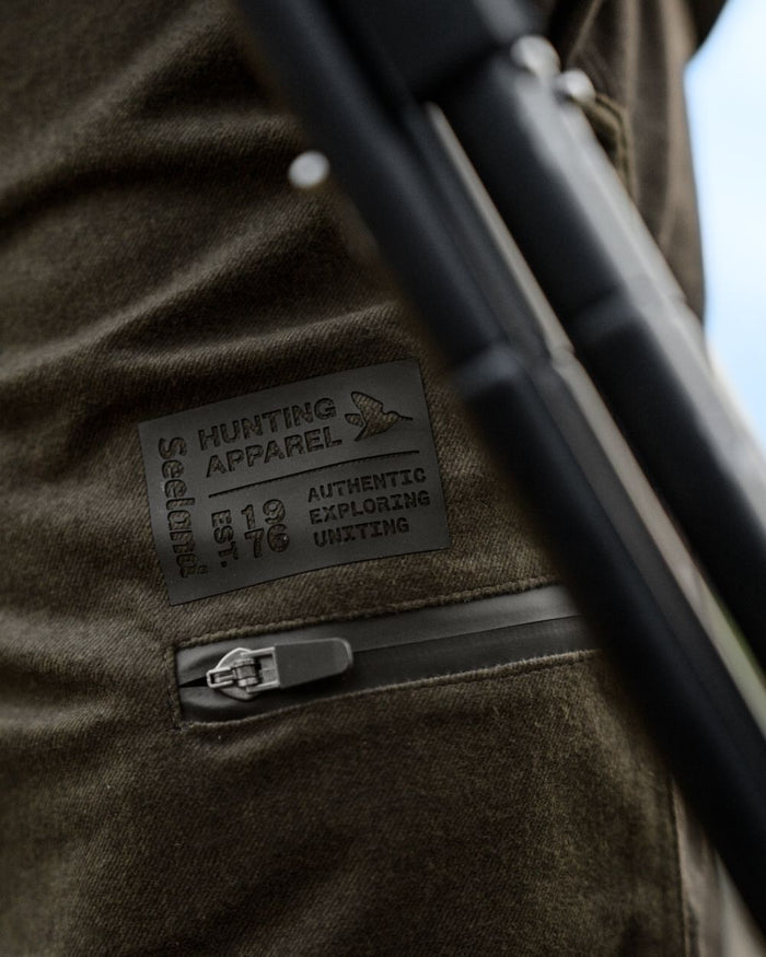 Pine Green Melange coloured Seeland Mens Quest Trousers on forest background #colour_pine-green-melange