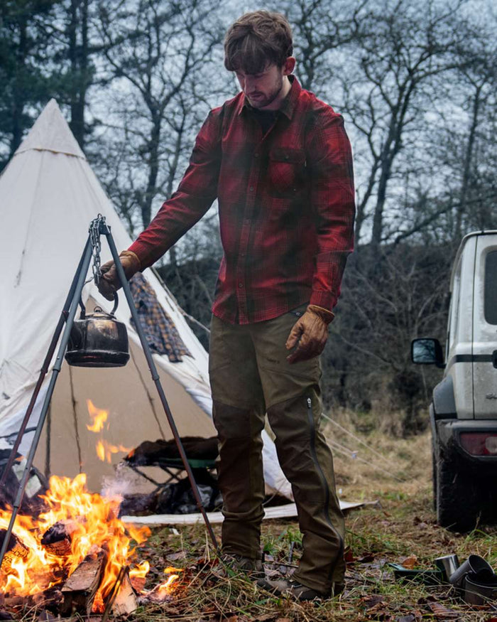 Pine Green Grizzly Brown coloured Seeland Mens Spruce Membrane Trousers on forest background #colour_pine-green-grizzly-brown