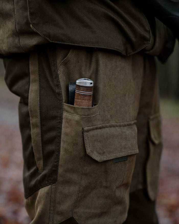 Grizzly Brown coloured Seeland Mens Ultimo Trousers on forest background #colour_grizzly-brown