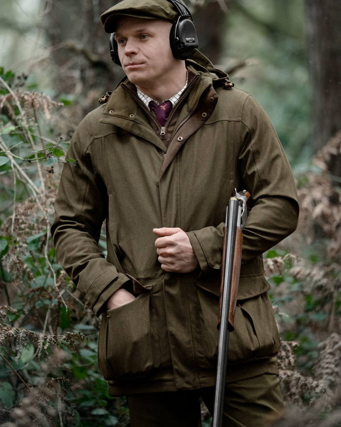 Shaded Olive coloured Seeland Mens Woodcock Royale Jacket on forest background #colour_shaded-olive