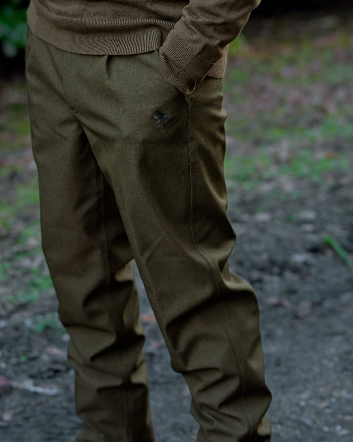 Shaded Olive coloured Seeland Mens Woodcock Royale Trousers on forest background #colour_shaded-olive