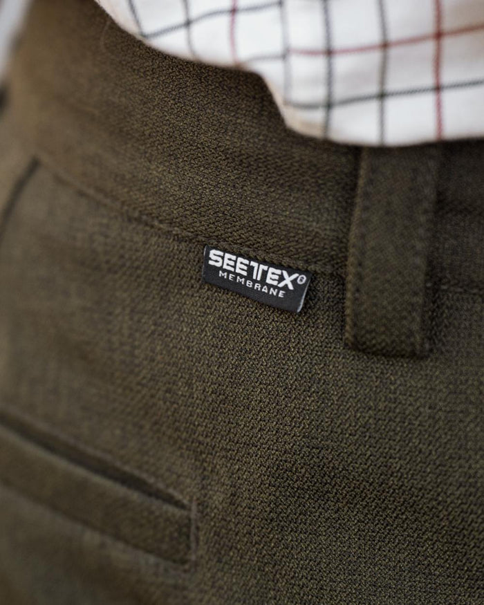 Shaded Olive coloured Seeland Mens Woodcock Royale Trousers on forest background #colour_shaded-olive