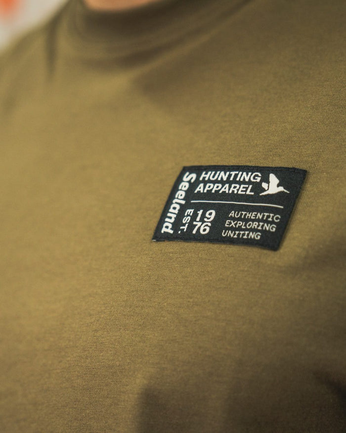 Military Olive Coloured Seeland Striker T-Shirt on indoor background #colour_military-olive
