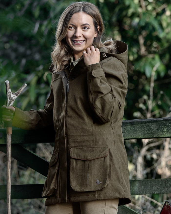 Shaded Olive coloured Seeland Womens Woodcock Royale Eve Jacket on forest background #colour_shaded-olive