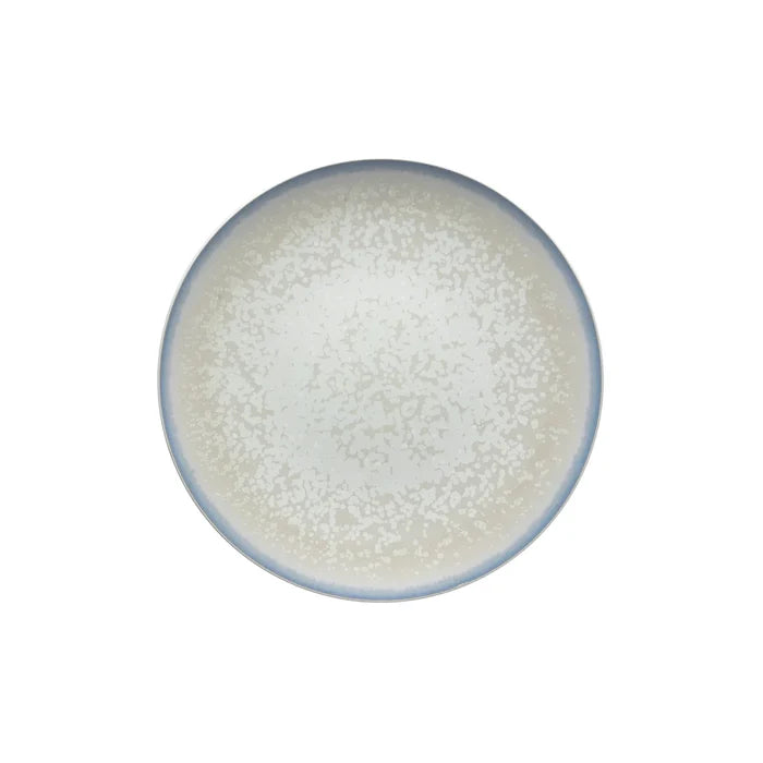 The Song Dinnerware Perle - Agoro plate by Jaune De Chrome features a high-fired porcelain build, subtle speckling, a light beige center, and soft blue-gray rim. Shown from above on white, it adds elegance to any table setting.