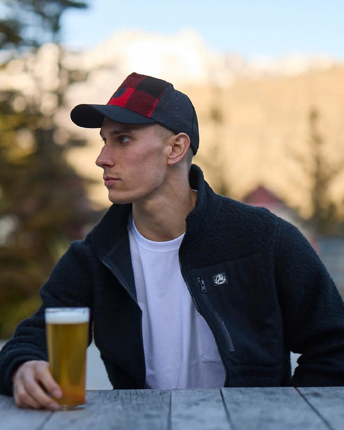 Red Black Check Coloured Swanndri Swanni Trucker Cap on blurry background #colour_red-black-check