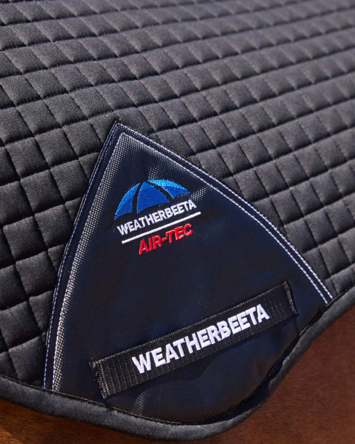 Black Coloured WeatherBeeta Prime Air-Tec Jump Shaped Saddle Pad on horse  background #colour_black