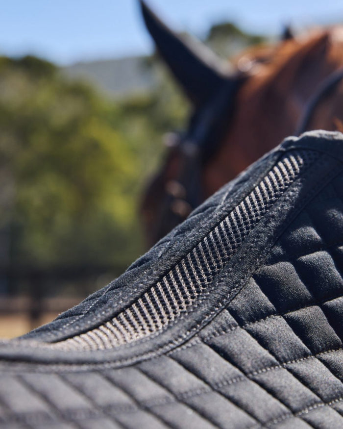 Black Coloured WeatherBeeta Prime Air-Tec Jump Shaped Saddle Pad on horse background #colour_black