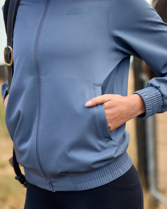 Slate Blue coloured WeatherBeeta Womens Waterproof Team Jacket on outdoor background #colour_slate-blue