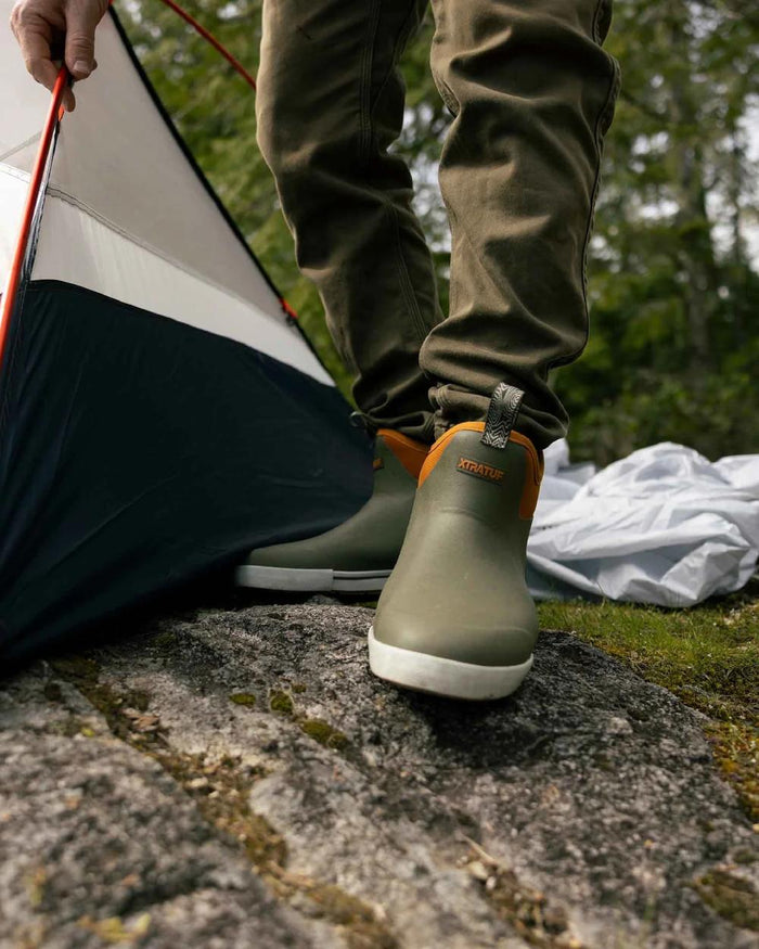 Olive Coloured Xtratuf Womens 6" Ankle Deck Camp Boots on forest background #colour_olive